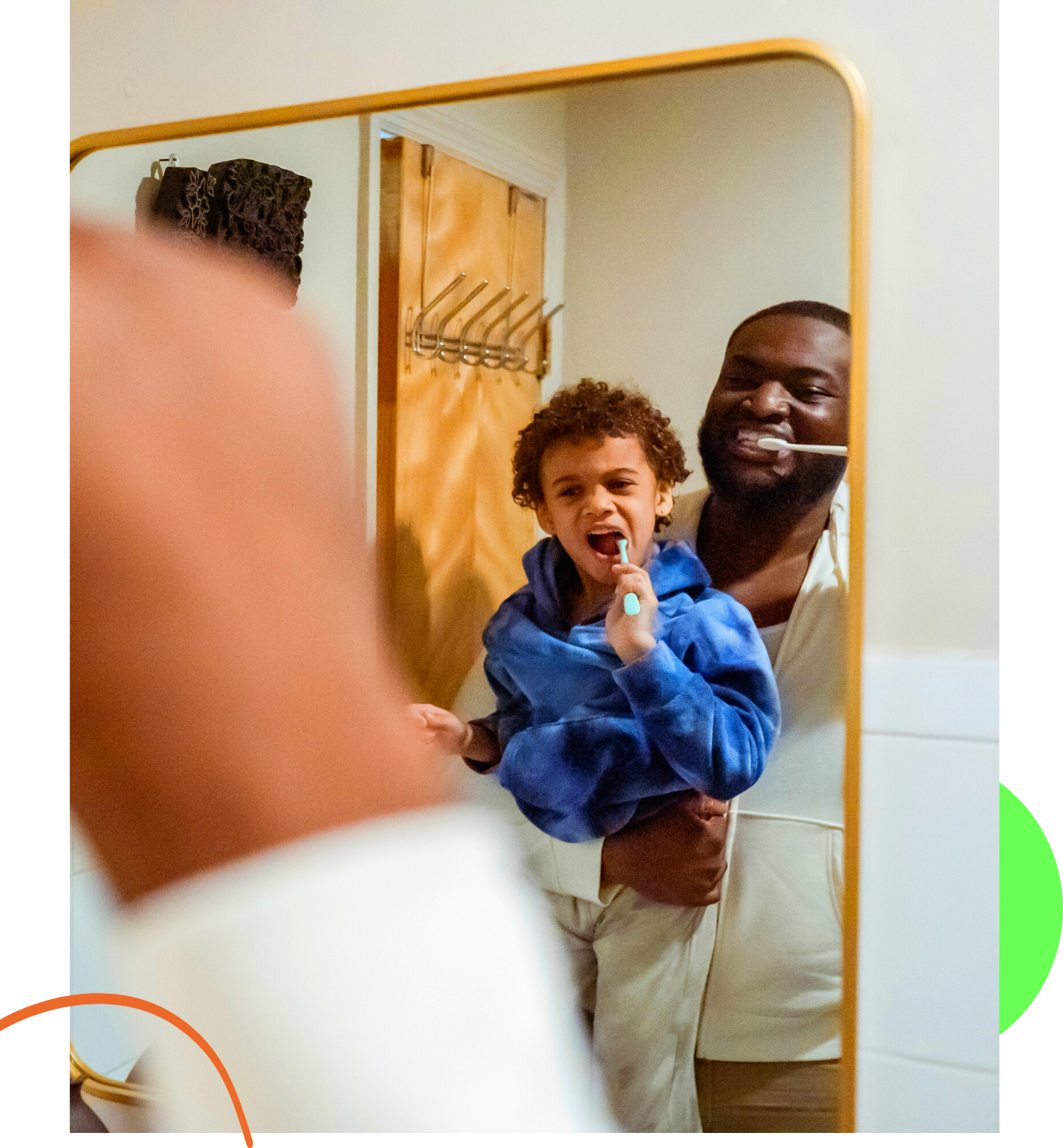 Dad holding his son both brushing their teeth in a mirror